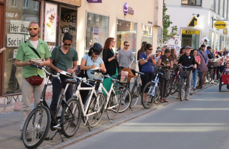Students stand alongside their bikes on sidewalk in Denmark